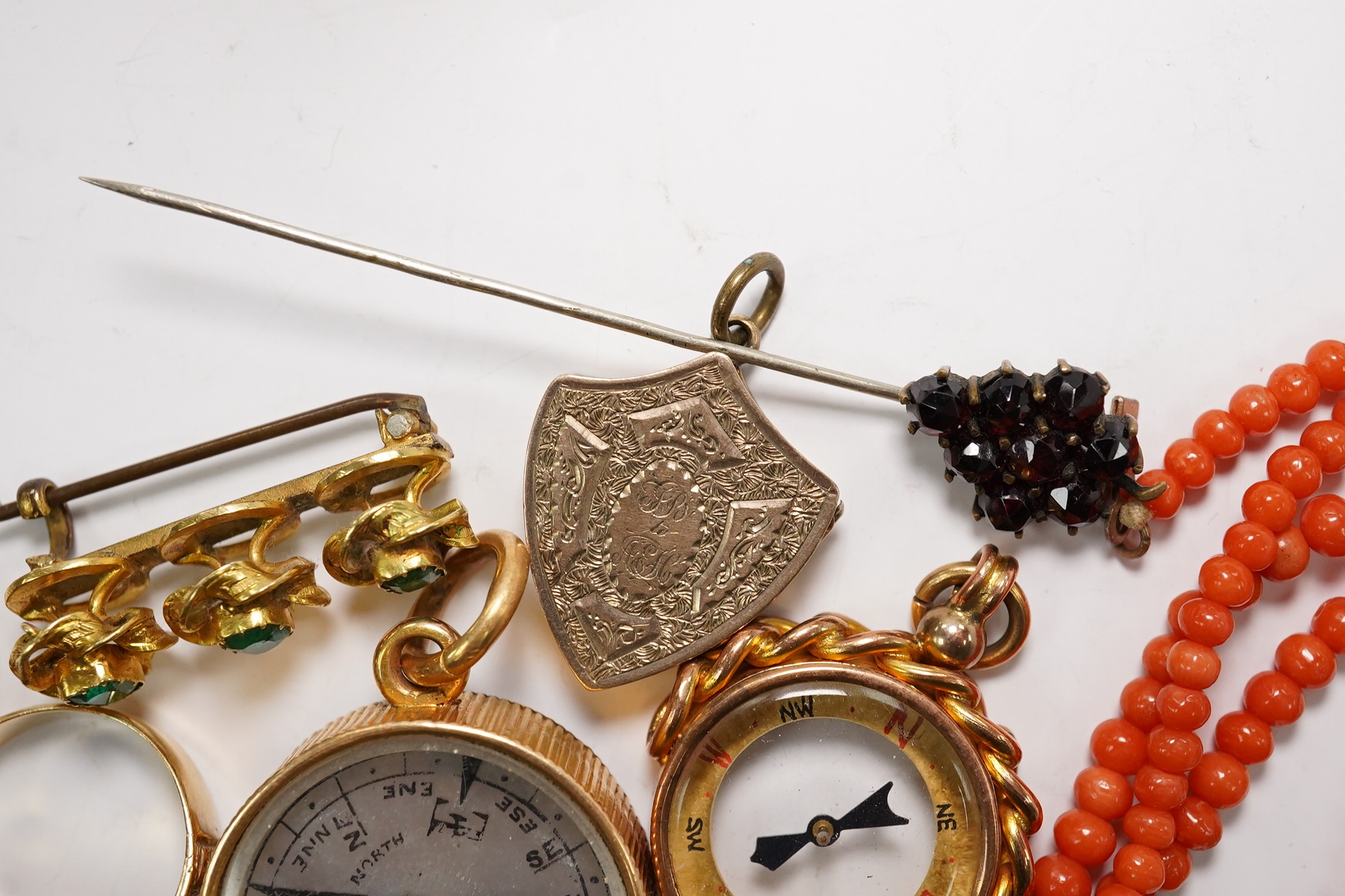 A small group of assorted jewellery including a coral necklace, 9c compass fob, five yellow metal items including a ring, locket and brooch and a stick pin. Condition - poor to fair